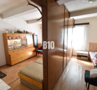Wohnzimmer in einem Einfamilienhaus mit Möbeln und Boden in Holzoptik.