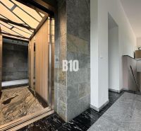 Der Flur mit stilvollem Aufzug in einer 2-Zimmer-Wohnung, mit Steinwänden und Steinboden.