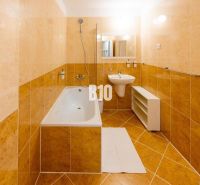 Badezimmer in einer Ferienwohnung mit Badewanne, Waschbecken und hellen Fliesen.