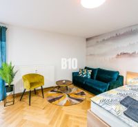 Stilvolles Ferienapartment mit Holzboden, Sofa und Pflanzen.