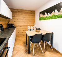 Innenraum einer Ferienwohnung mit Küche, Esstisch und Boden in Holzoptik.