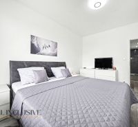 Schlafzimmer in einer 3-Zimmer-Wohnung mit Doppelbett, Fernseher und Holzboden.