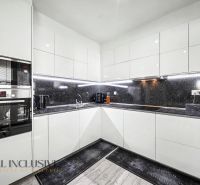Küche einer 3-Zimmer-Wohnung mit weißen Schränken und schwarzer Arbeitsplatte.