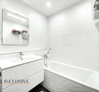 Ein Badezimmer mit weißen Fliesen und einem Waschbecken in einer 3-Zimmer-Wohnung.