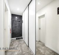 Ein Flur mit weißen Wänden, einem Schiebeschrank und einem Steinboden in einer 3-Zimmer-Wohnung.