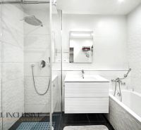 Badezimmer mit moderner Duschkabine und Badewanne in einer 3-Zimmer-Wohnung mit weißen Fliesen.