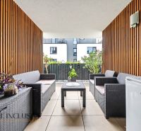 Möblierte Terrasse einer 3-Zimmer-Wohnung mit Rattanmöbeln und Blumendekoration.