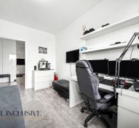 Ein Arbeitszimmer mit Computer, Regalen und einem Boden in Holzoptik in einer 3-Zimmer-Wohnung.