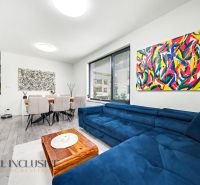 Wohnzimmer einer 3-Zimmer-Wohnung mit bunten Bildern, einem blauen Sofa und einem Esstisch.