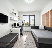 Ein Zimmer in einer 3-Zimmer-Wohnung mit einem Schreibtisch, einem Sofa und einem Boden in Holzoptik.