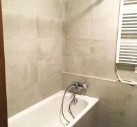 Badezimmer mit Badewanne und hellen Fliesen in einer 2-Zimmer-Wohnung.