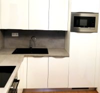 Weiße Küche mit Mikrowelle und eingebautem Spülbecken, 2-Zimmer-Wohnung, Boden mit Holzdekor.