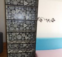 Ein Bücherregal mit geometrischem Muster neben einem bunten Sofa in einer Zweizimmerwohnung.