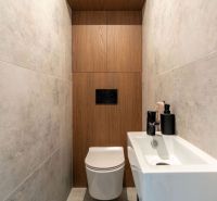 Ein Badezimmer mit einem Boden in Holzoptik und einer weißen hängenden Toilette in einer Zweizimmerwohnung.