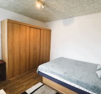 Schlafzimmer in einer 4-Zimmer-Wohnung mit Bett, Schrank und Boden mit Holzdekor.