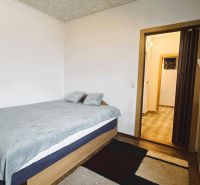 Schlafzimmer in einer 4-Zimmer-Wohnung mit Bett, Teppich und Möbeln in Holzoptik.
