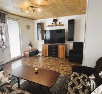 Wohnzimmer in einer 4-Zimmer-Wohnung mit Holzboden und einem Fernseher an der Wand.