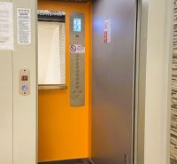 Ein offener Aufzug in einem Gebäude mit einer 4-Zimmer-Wohnung mit orangem Interieur.