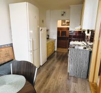 Küche in einer 4-Zimmer-Wohnung mit Holzboden, Esstisch und Geräten.
