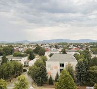 Blick auf die Komenského-Straße in Trebišov mit Gebäuden und Grünflächen.