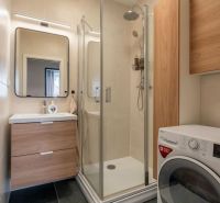 Badezimmer in einer 3-Zimmer-Wohnung mit Waschmaschine, Dusche und Waschbecken mit Stauraum.