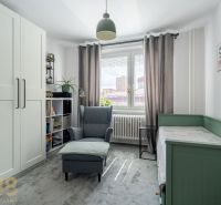 Helles Zimmer mit Sessel, Bett, Kleiderschrank und Dekorationen in einer 3-Zimmer-Wohnung.