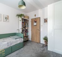 Ein Zimmer in einer 3-Zimmer-Wohnung mit einem Bett, Büchern, Pflanzen und einer Lampe.