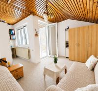 Ein helles Zimmer in einem Einfamilienhaus mit einer Couchgarnitur und einem Kleiderschrank.