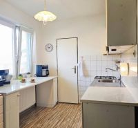 Küche in einem Einfamilienhaus mit Holzboden und weißen Schränken.