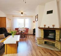 Ein Zimmer eines Einfamilienhauses mit Kamin, Sitzgarnitur und einem Boden mit Holzdekor.