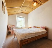 Schlafzimmer in einem Einfamilienhaus mit Holzdecke, Teppich und Bett mit Kissen.