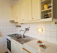 Küche in einem Einfamilienhaus mit weißen Schränken und Theke, Boden mit Holzdekor.