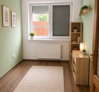 Ein Zimmer mit Holzelementen, Teppich und Pflanzen in einem Einfamilienhaus.