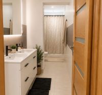Badezimmer in einem Einfamilienhaus mit Doppelwaschbecken und schwarzen Matten, frische Dekorationen.