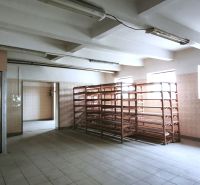 Produktionsräume mit Regalen und Aufzug, beleuchtet durch Fenster, mit Keramikboden.