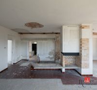Ein Einfamilienhaus mit Kamin, unverputzte Wände und Fliesen im Innenraum.
