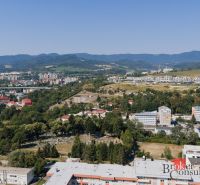 Blick auf das Panorama von Banská Bystrica von der Komenského-Straße, man sieht Einfamilienhäuser und Natur.