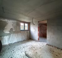 Unvollendeter Innenraum eines Einfamilienhauses mit unverputzten Wänden und Betonboden.
