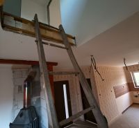 Innenrenovierung in einem Einfamilienhaus, dominiert von Treppen und einem Holzofen.