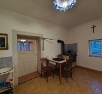 Küche in einem Einfamilienhaus mit einem Ofen, einem einfachen Tisch und einem Stuhl.