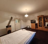 Schlafzimmer in einem Einfamilienhaus mit dunklem Boden, Möbeln, Fernseher und Ofen.