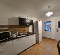 Küche in einem Einfamilienhaus mit braunen Fliesen, ausgestattet mit Mikrowelle und Kühlschrank.
