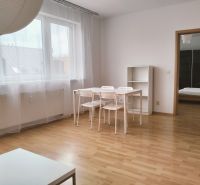 2-Zimmer-Wohnung mit Holzbodenoptik, weißem Tisch und durchsichtigen Vorhängen.
