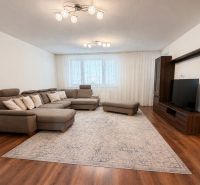 Wohnzimmer mit großem Sofa, Fernseher und Holzboden in einem Einfamilienhaus.