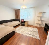 Zwei Betten, ein Schreibtisch und ein Regal in einem Zimmer eines Einfamilienhauses mit einem Boden in Holzoptik.