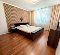 Schlafzimmer in einem Einfamilienhaus mit Bett, Vorhängen und Boden mit Holzdekor.