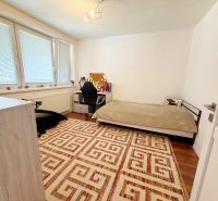 Ein Zimmer in einem Einfamilienhaus mit Teppichmuster und einem Boden in Holzoptik.