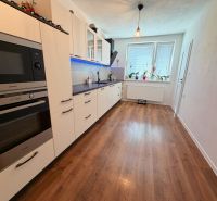 Küche in einem Einfamilienhaus mit weißer Küchenzeile und Boden in Holzoptik.