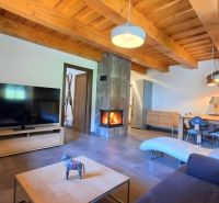 Wohnzimmer in einer Hütte mit Kamin, Fernseher und Holzbalkendecken.