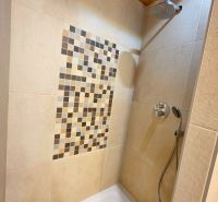 Duschkabine mit Mosaik an der Wand in der Hütte.